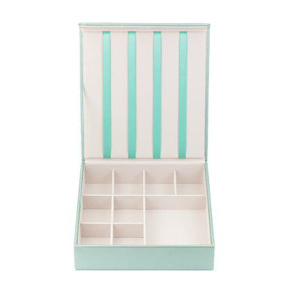 The mint green hair accessory organiser is shown against a white background. The box is empty and clearly shows the 4 ribbons attached to the lid which are designed to hold hair clips, and the grid in the bottom half which is designed to store hair bands, barrettes, hair bobbles and scrunchies